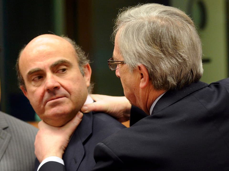 Juncker hält die Hände an den Hals des spanischen Wirtschaftsminister Luis de Guindos