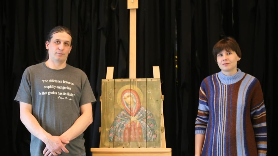 Ein Künstlerpaar präsentiert ein Ikonenbild auf einer Staffelei