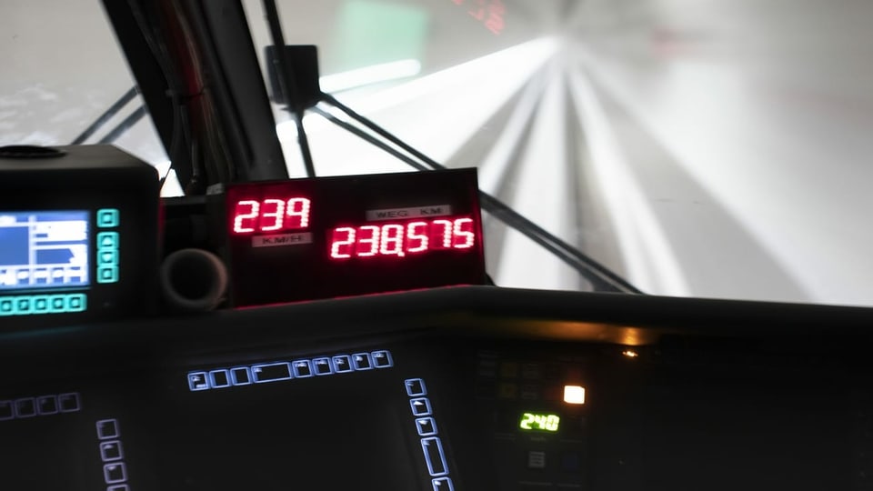 Eine LCD-Anzeige zeigt die Geschwindigkeit des Zuges an und durch die Scheiben des Führerstands sieht man einen hell erleuchteten Tunnel.