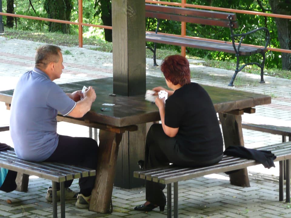 EIn Mann und eine Frau sitzen draussen und spielen Karten.