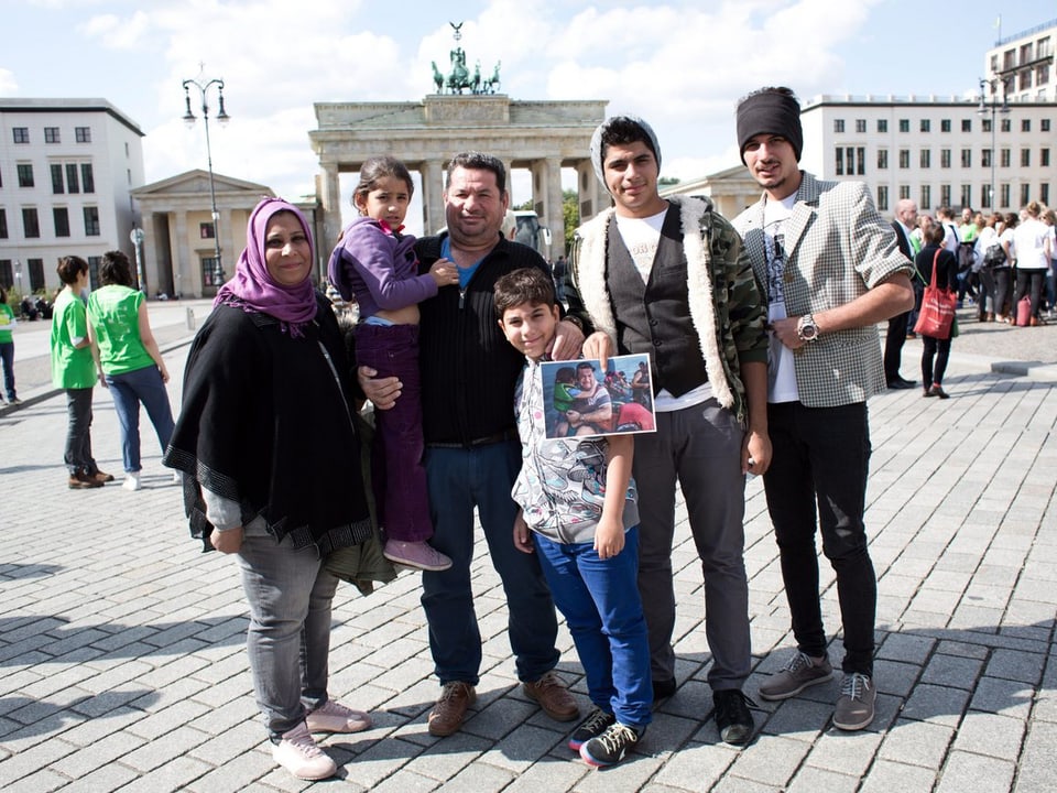 Ein irakischer Flüchtling mit seiner Familie vor dem Brandenburger Tor in Berlin