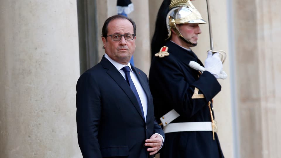 Hollande vor dem Präsidentenpalast, neben ihm ein Wachmann in historischer Uniform.