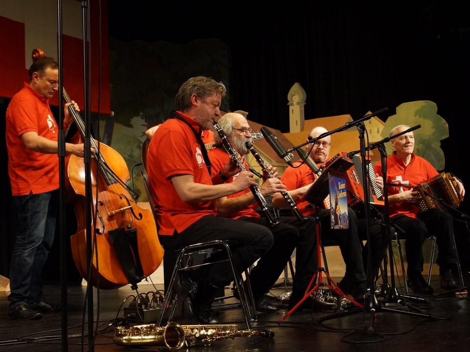 Eine Volksmusikformation mit Musikern in roten Shirts auf einer Bühne.
