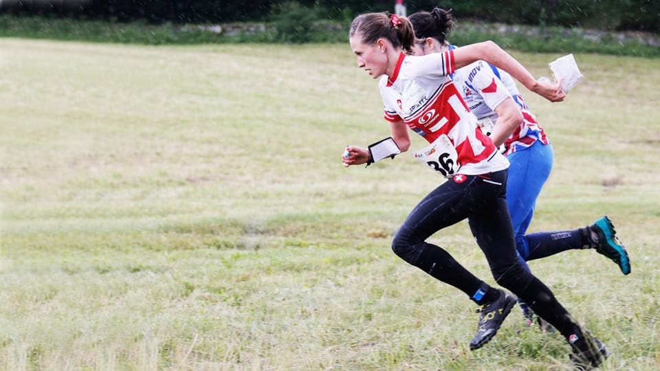Die Orientierungsläuferin Judith Wyder sprintet auf einer Wiese gegen eine Konkurrentin.