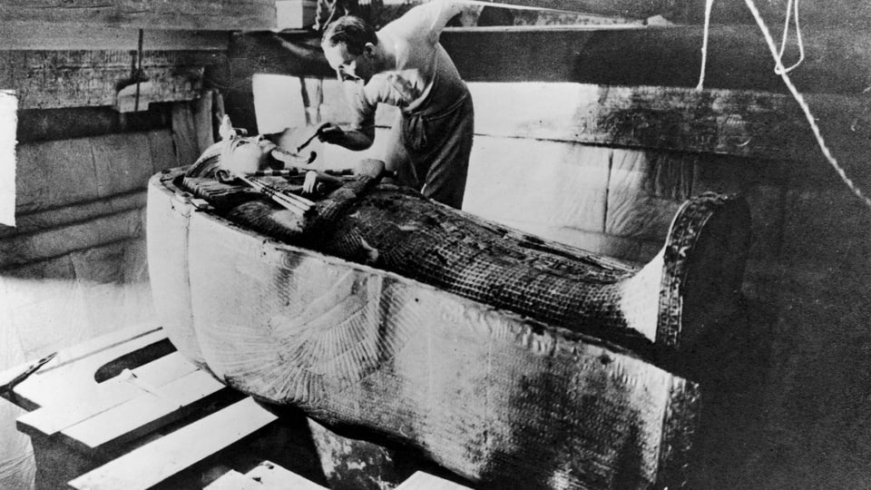 Howard Carter steht vor dem Sarg von Tutanchamun.