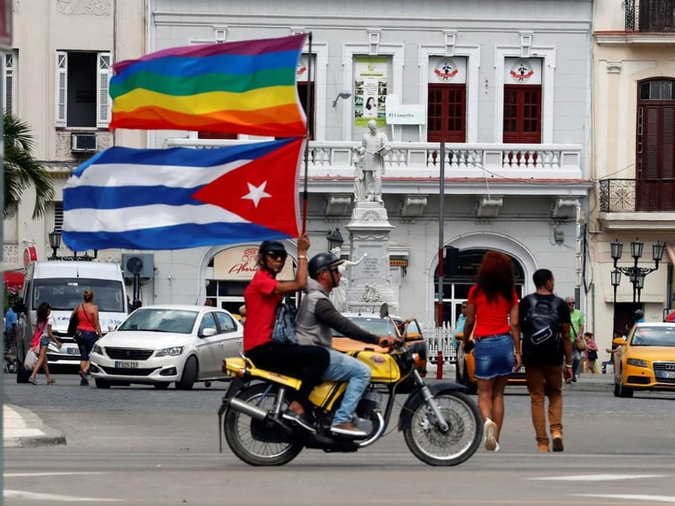Mann auf Töfff in Havana mit kubanischer und LGBT-Flagge