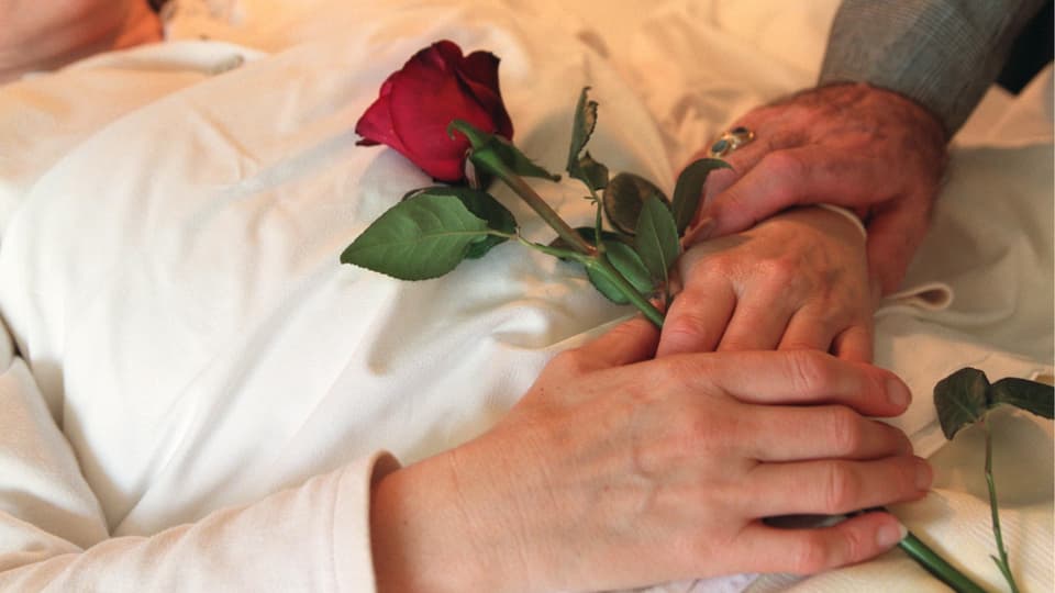 Eine Frau liegt mit eine Rose in der Hand im Bett