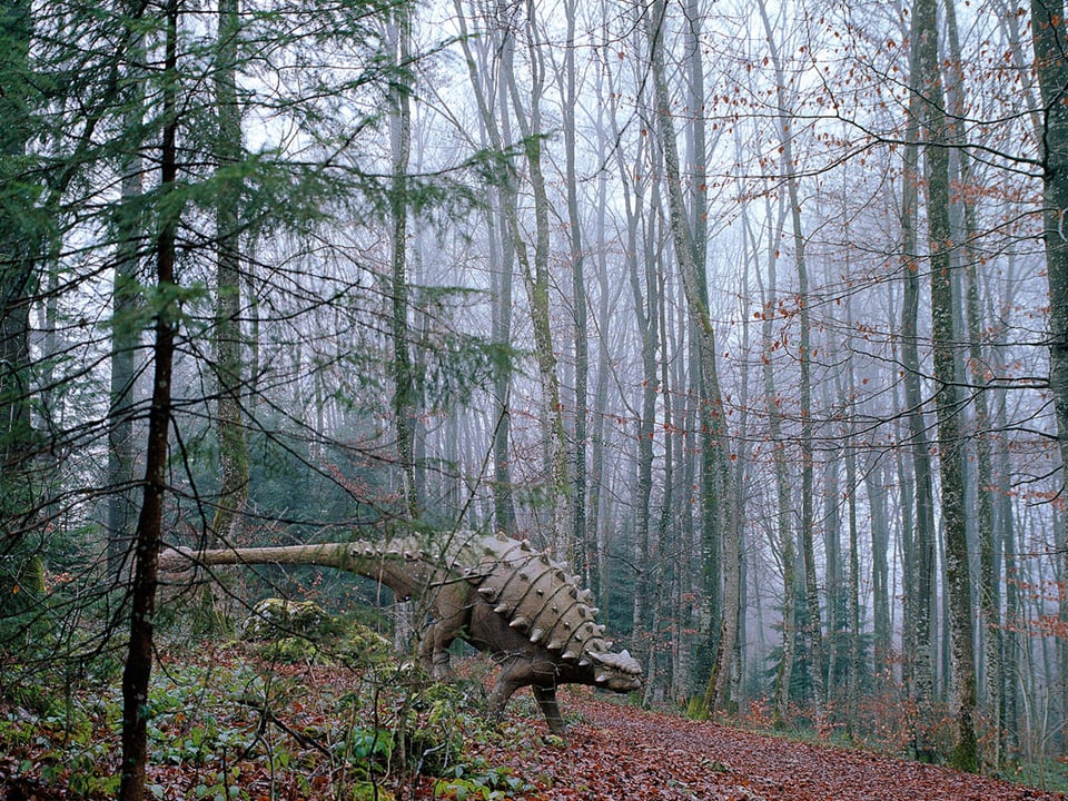 Figur eines Sauropoden im herbstlichen Wald.