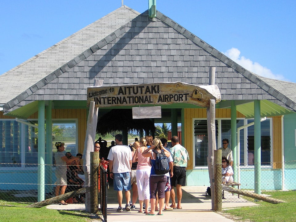 Touristen betreten das kleine Flughafen-Häuschen in Aitutaki auf den Cook-Inseln.