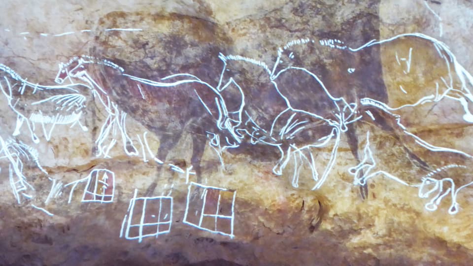 Weiss eingefärbte Ritzbilder von Pferden auf einer Felswand.