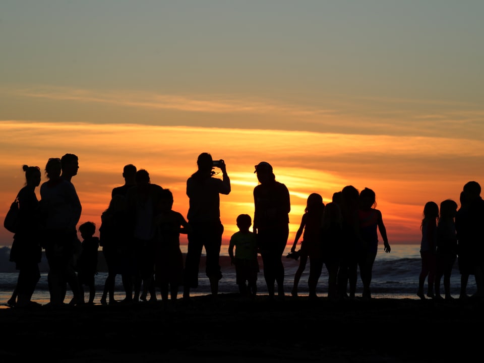 Familie bei Sonnenuntergang am Strand.
