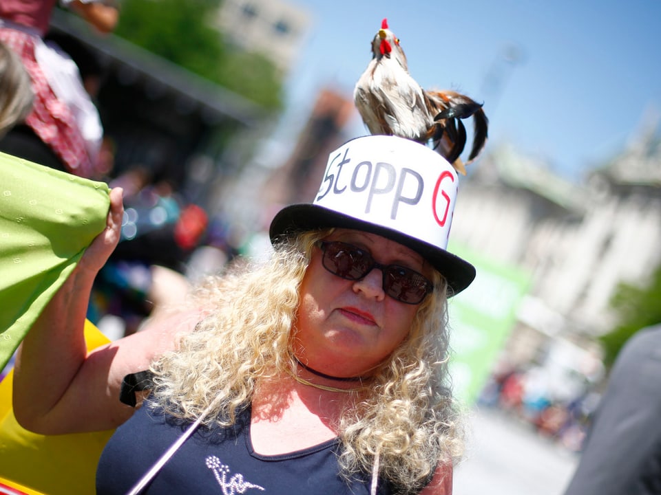Eine Demonstrantin mit einem Hut und einem Hahn auf dem Kopf