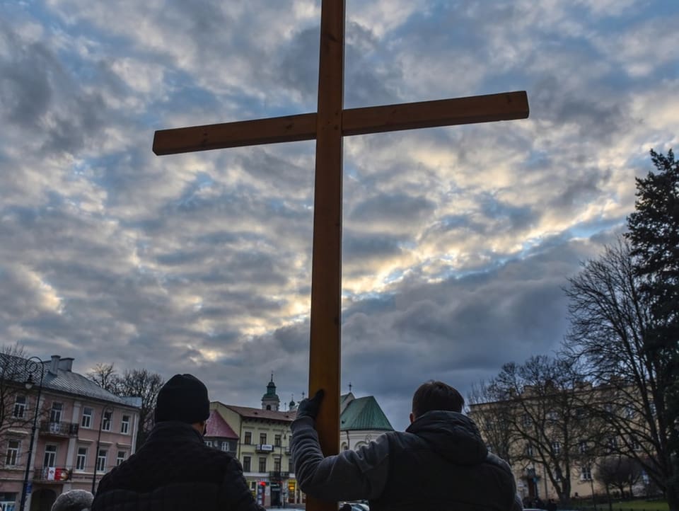 Two men holding a large wooden cross