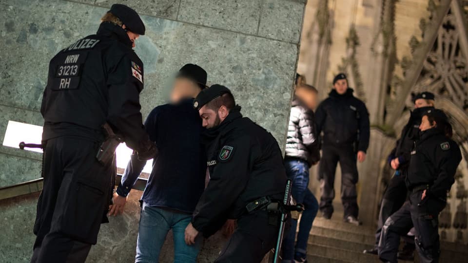 Kölner Polizisten untersuchen Verdächtige vor dem Dom.