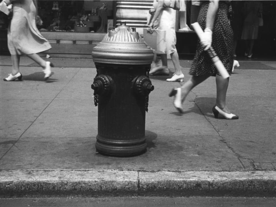 Auf einem schwarz-weissen Foto ist ein Hydrant auf einem Bürgersteig zu sehen.