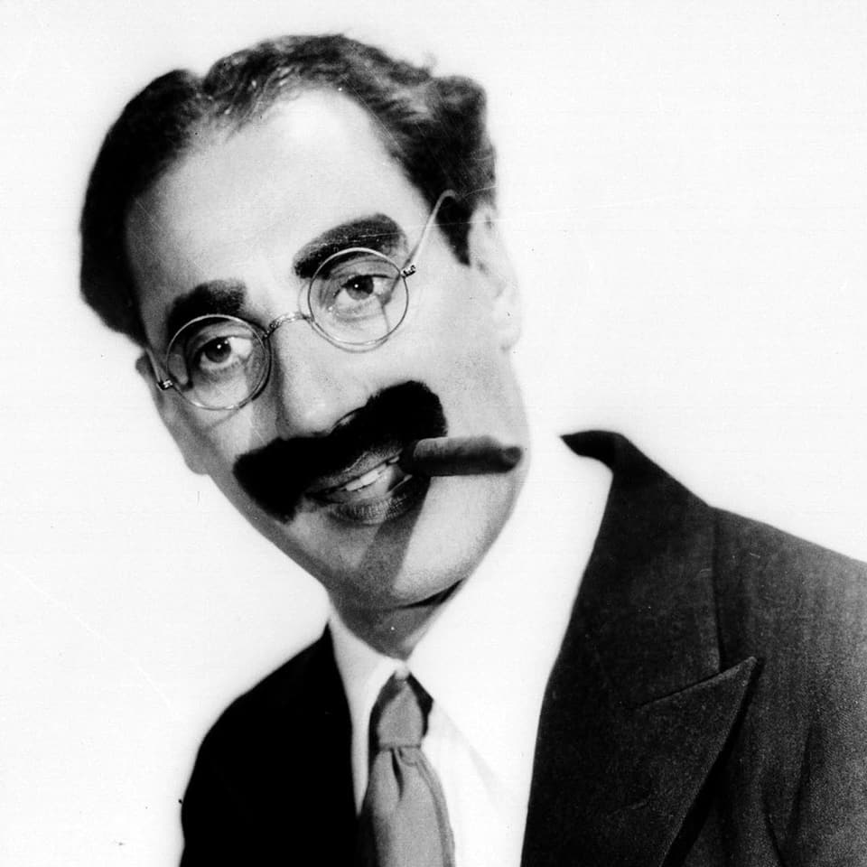 Groucho Marx posiert mit einer Zigarre im Mund.