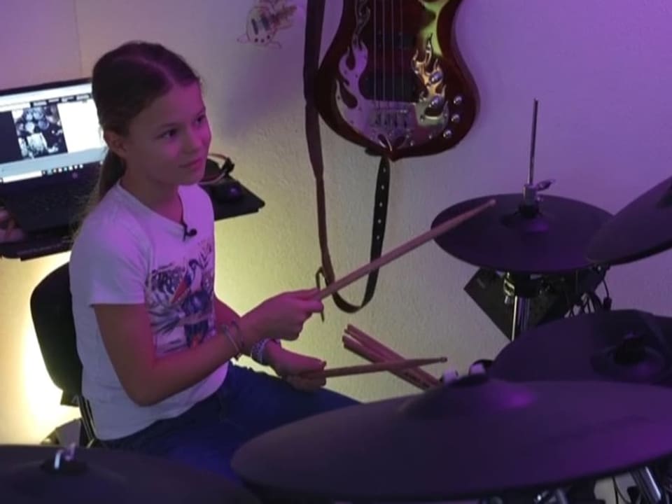 Nina spielt Schlagzeug im Zimmer. 