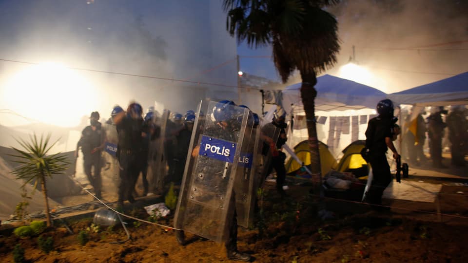 Polizisten im Tränengasnebel bei Nacht.