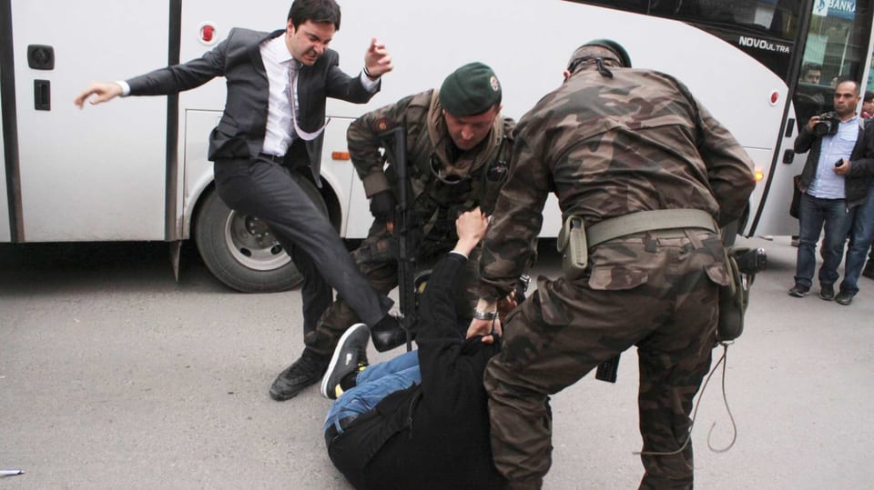 Yerkel schlägt kraftvoll gegen einen am Boden liegenden Demonstranten.