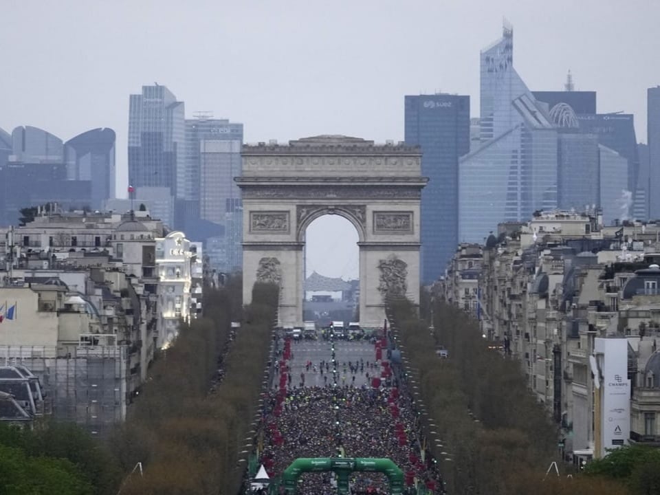 Blick auf den Triumphbogen und die Champs-Élysées mit Menschenmenge und modernen Gebäuden im Hintergrund.