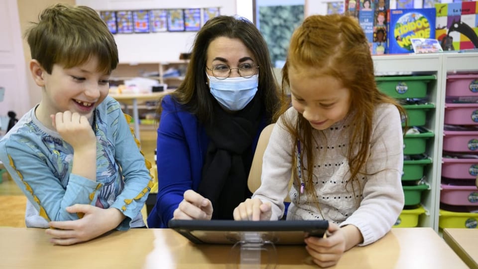 Lehrerin erklärt Kindern was auf dem iPad.