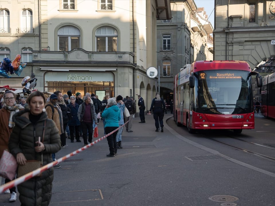 Menschen warten vor abgesperrter Strasse.