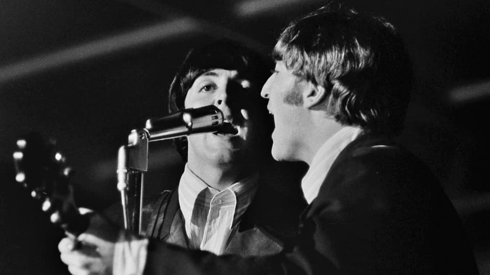 McCartney und Lennon singen ins selbe Mikrofon.