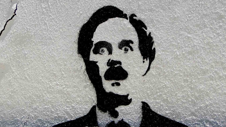 Schablonen Graffiti auf einer grauen Hauswand.
