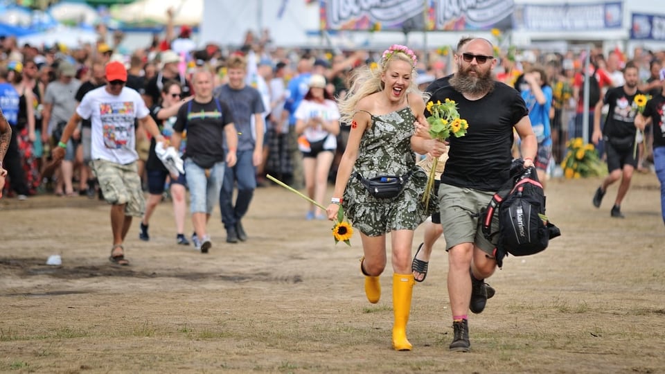 Leute rennen auf einem Festivalgelände.