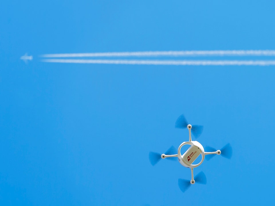 Drohne vor Kondensstreifen eines Jets.