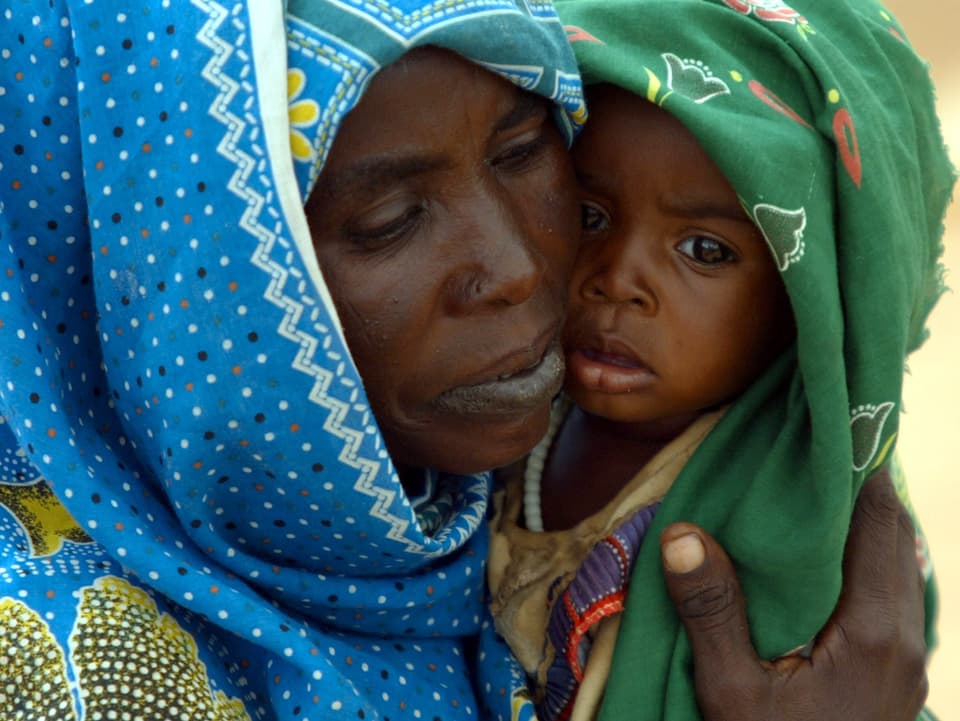 Sudanesische Frau hält Kind auf dem Arm.
