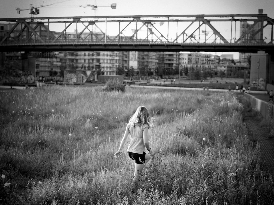 Ein Mädchen läuft durch das hohe Gras des Berliner Parks am Gleisdreieck.