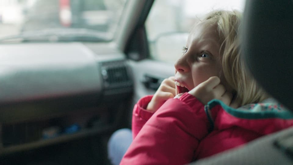 Ein Mädchen sitzt auf dem Beifahrersitz eines Autos und schreit
