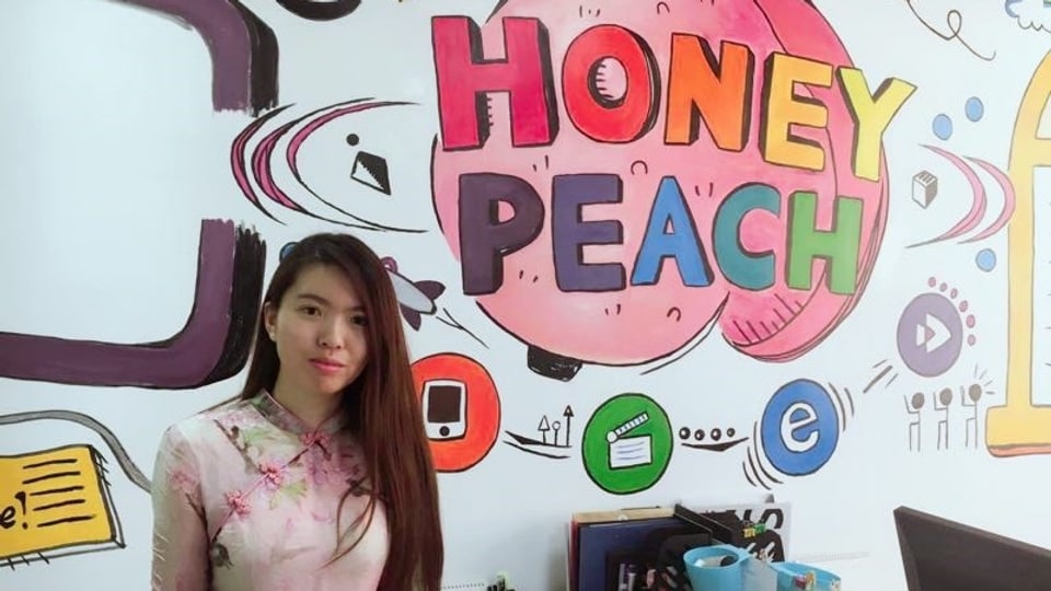Die Chinesin Wang Yilin steht vor einem Logo ihrer Firma «Honey Peach».