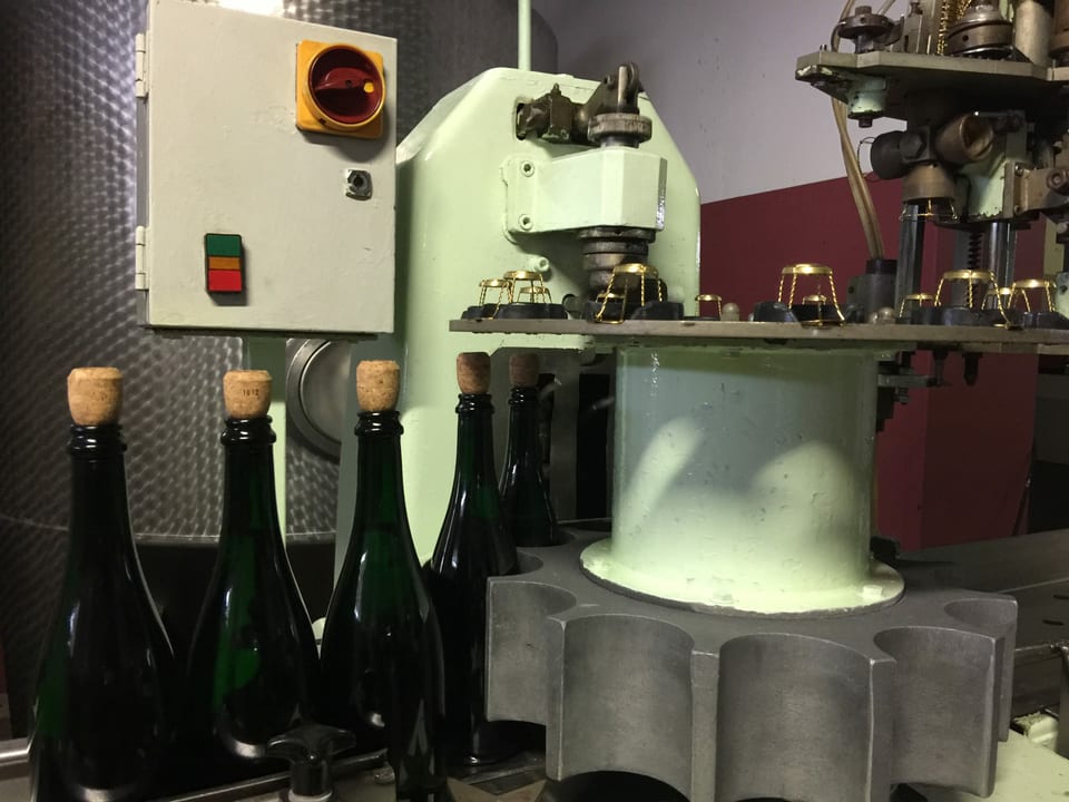 Flaschen in einer Maschine, oben warten Drahtgeflechte auf Einsatz.