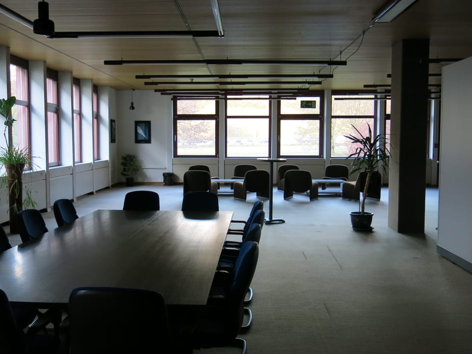 EIn Konferenzsaal mit Tischen und Stühlen - aber ohne Licht.