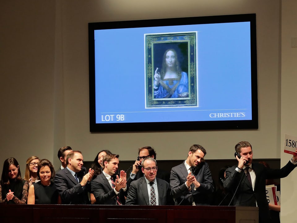 Leute applaudieren unter einem projizierten Bild von da Vinci