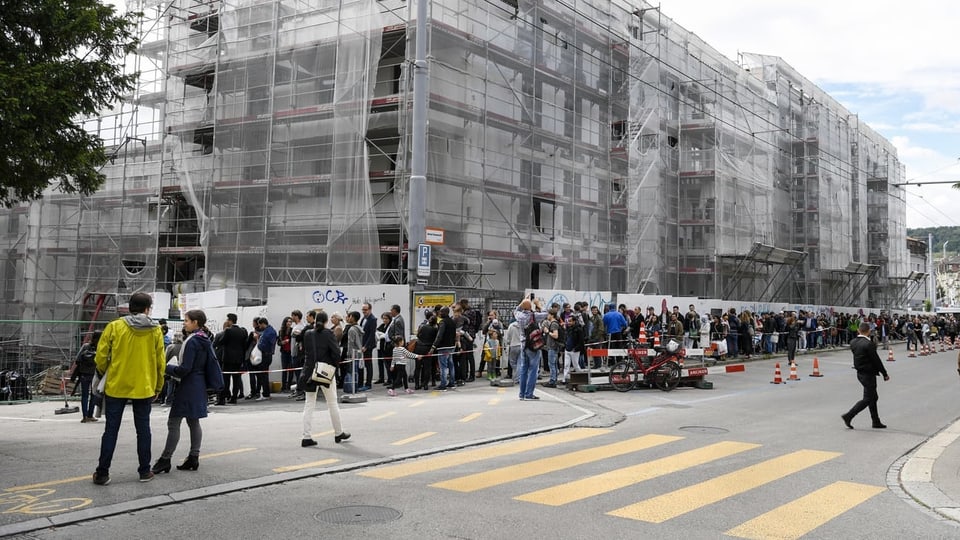 Hunderte Menschen stehen Schlange, um neue Wohungen in der Nähe des Bucheggplatzes in Zürich besichtigen zu können.
