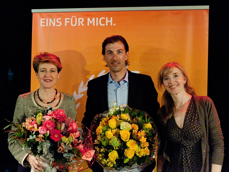 Simonetta Sommaruga und Fabian Cancellara posieren mit Blumen neben Anita Richner.
