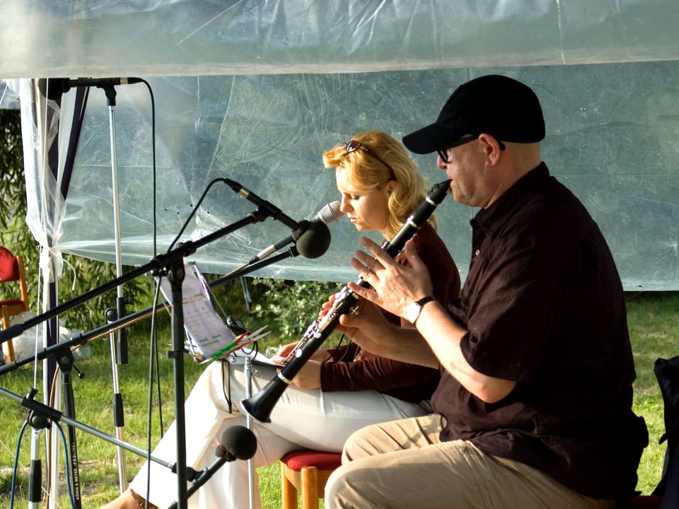 Mann und Frau sitzen in Zelt, Mann musiziert.