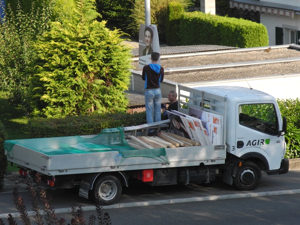 Wahlhelfer montieren Kandelaber-Plakate mit Lastwagen