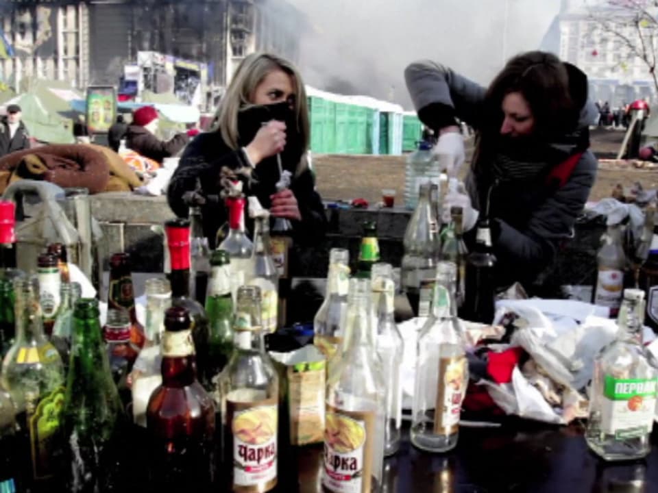 Zwei junge Frauen füllen Spirituosen-Flaschen mit Benzin für Molotow-Cocktails.
