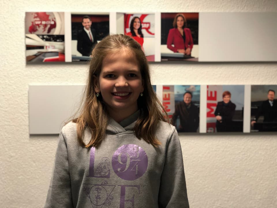 Mädchen Victoria steht vor einer Fotogalerie.