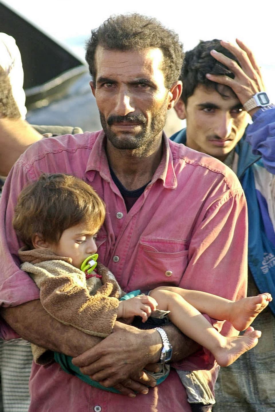 Ein Flüchtling hält sein schlafendes Kind in den Armen.
