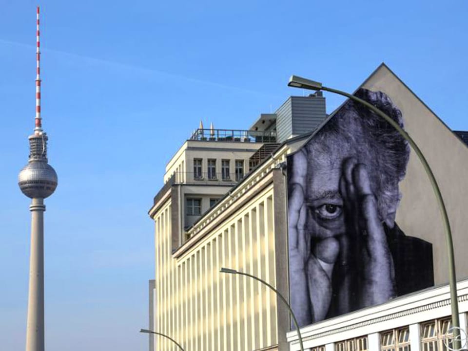 Fernsehturm Alexanderplatz und Hausfassade, mit Bild eines Männerkopfs