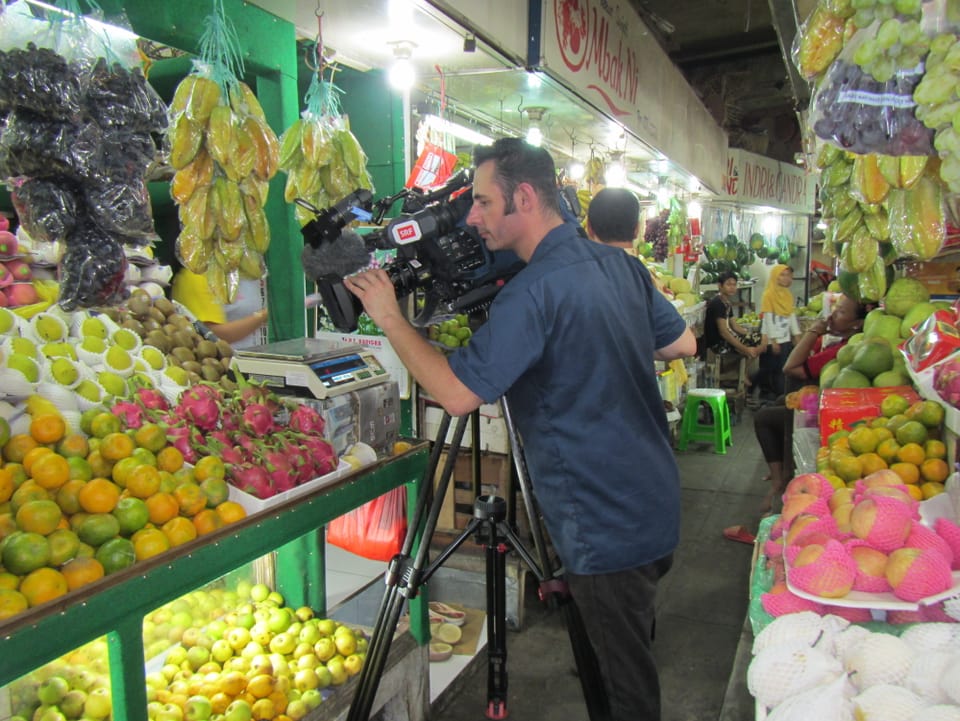 Kameramann filmt Früchte auf einem Markt in Solo, Indonesien.