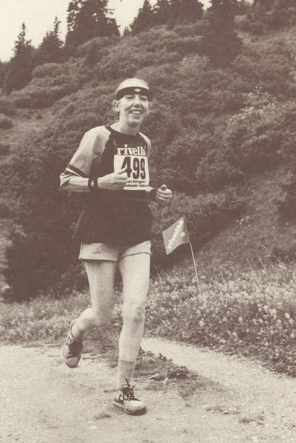 Frau mit Stirnband und kurzen Hosen auf Feldweg joggend.