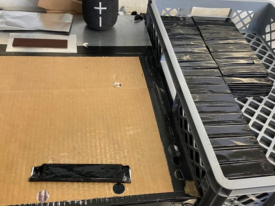 Schritt 6: Verpacken Rechts sind in schwarze Folie verpackte Schokoladen aufeinandergestapelt. Rechts ein Karton.