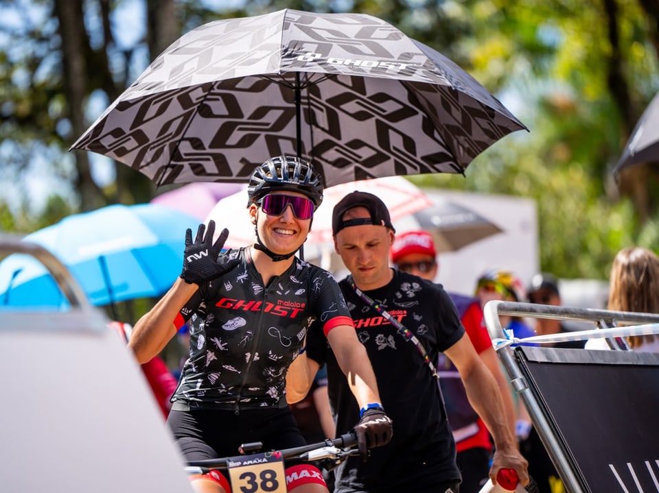 Zwei Mountainbiker mit Startnummern unter einem Schirm bei einem Rennen