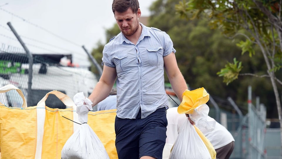 Ein Bewohner von Morningside, ein Vorort von Brisbane, trägt Sandsäcke.